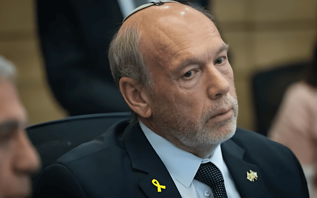 Hombre con kippah y lazo amarillo en traje oscuro.