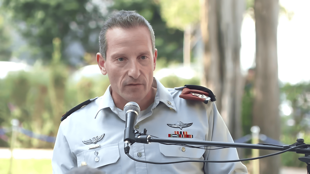 Hombre militar uniformado hablando en micrófono en exterior.