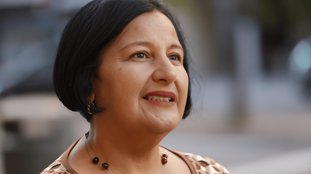 Mujer sonriente mirando hacia arriba, pelo oscuro, labios rojos.