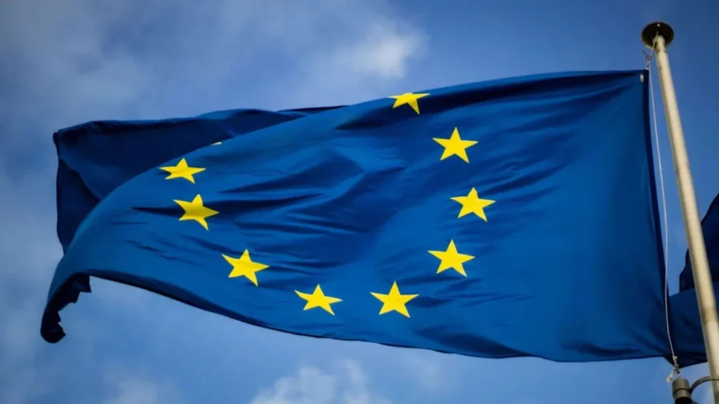 Bandera de la Unión Europea ondeando contra un cielo azul claro.
