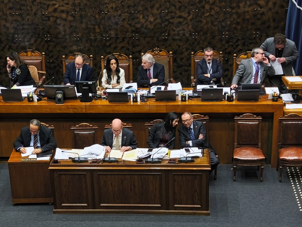 Funcionarios discutiendo en una sesión parlamentaria o reunión formal.