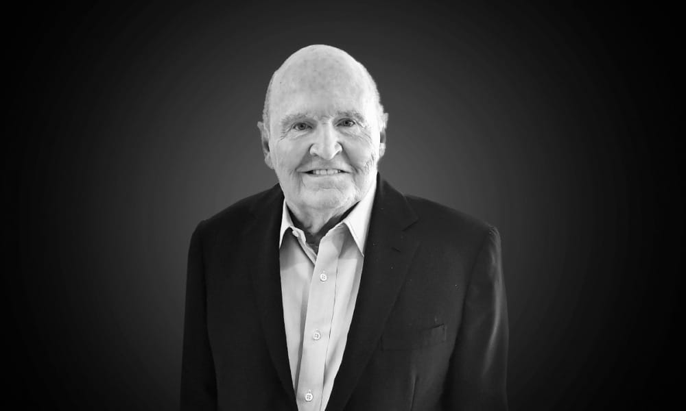 Retrato en blanco y negro de un hombre mayor sonriente con traje.