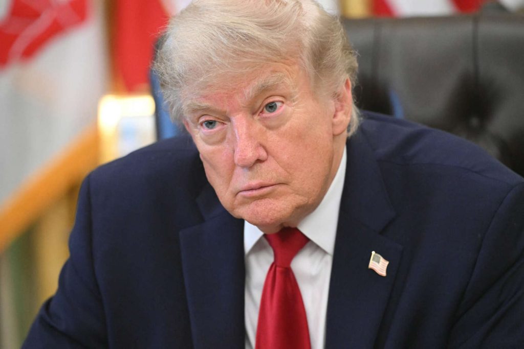 Donald Trump con traje oscuro y corbata roja, mirada seria.