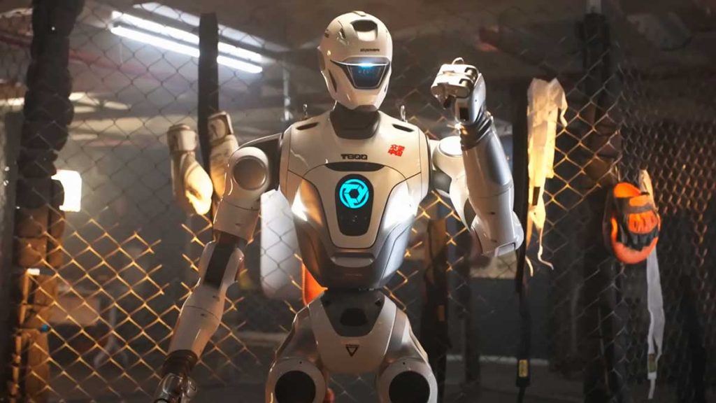 Robot blanco preparándose en un ring de boxeo o jaula.