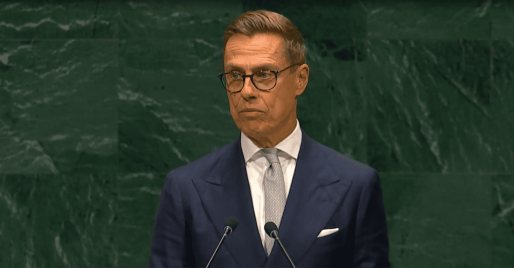 Hombre en traje y gafas hablando en un atril.