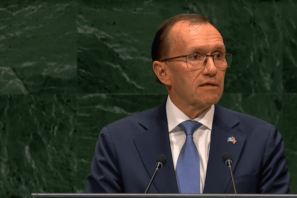 Hombre con gafas en traje azul hablando desde un podio.