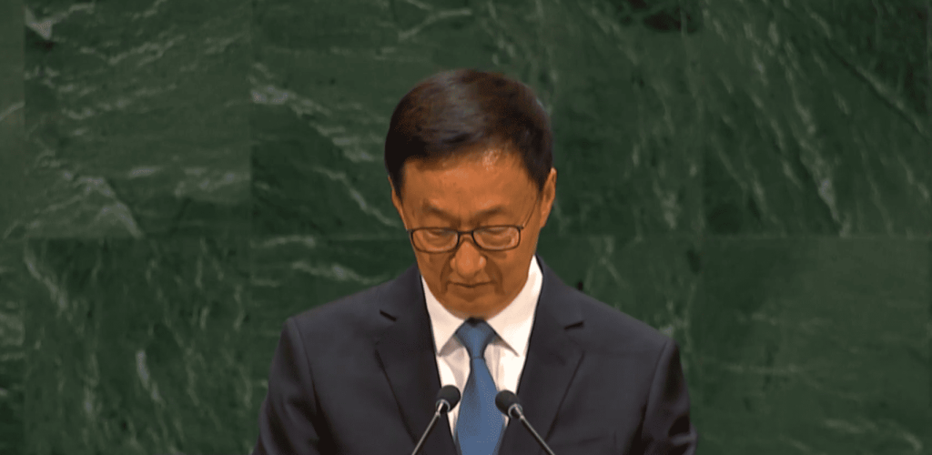 Hombre asiático con gafas dando un discurso formal.