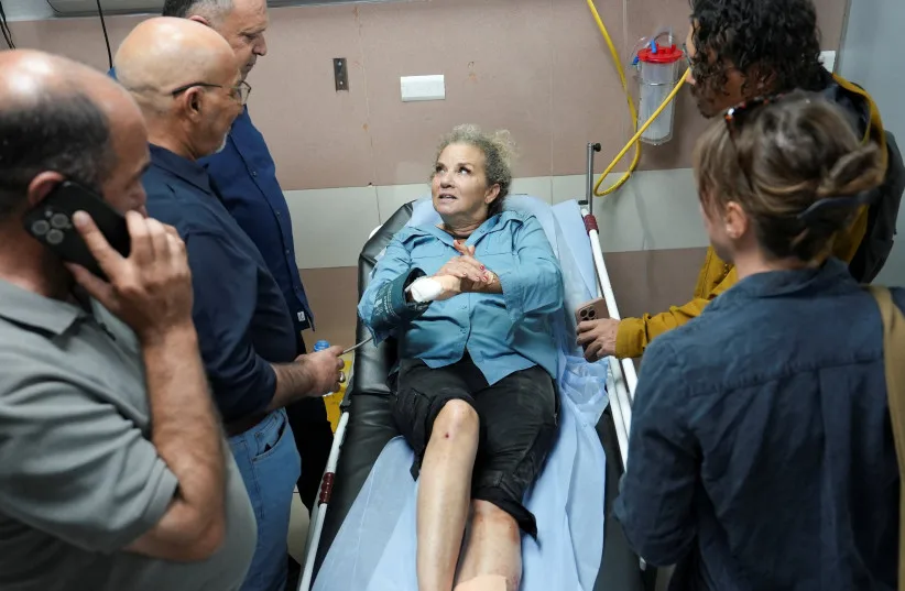 Mujer herida en camilla de hospital rodeada de personas.