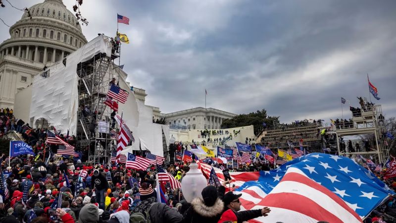 Asalto al Capitolio de EE.UU. con multitud y banderas americanas.