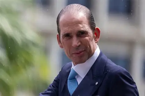 Hombre elegantemente vestido con traje azul marino y corbata.