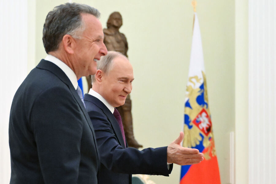 Putin sonríe y extiende la mano en un encuentro formal.