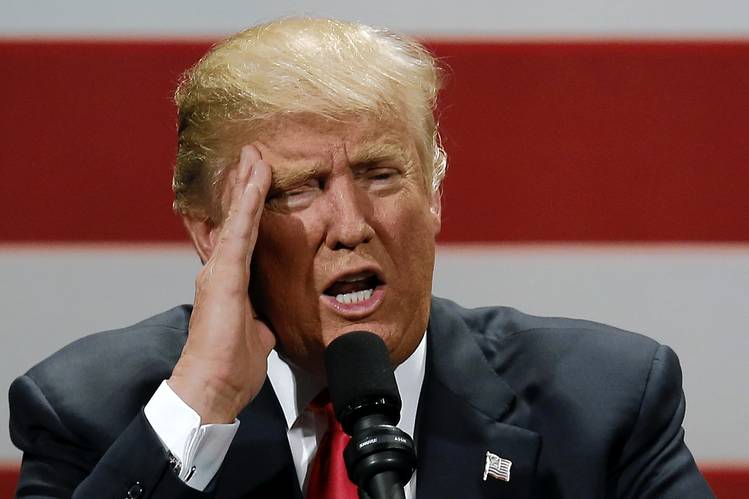 Donald Trump hablando con la mano en la frente en evento.