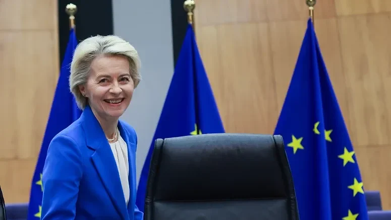 Ursula von der Leyen sonriendo ante banderas de la Unión Europea.